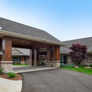 A building with a covered entrance and landscaped surroundings.