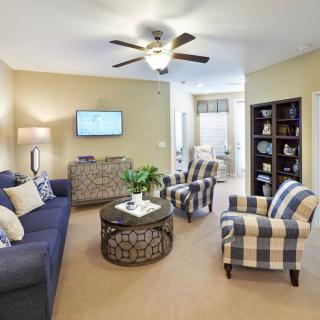 A cozy living room with a sofa, armchairs, coffee table, and ceiling fan.