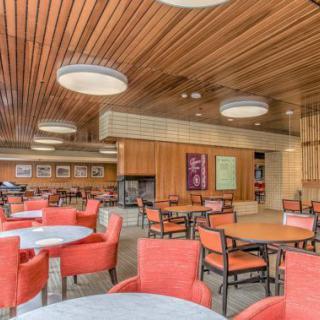 A modern cafeteria with red chairs and wooden ceiling.