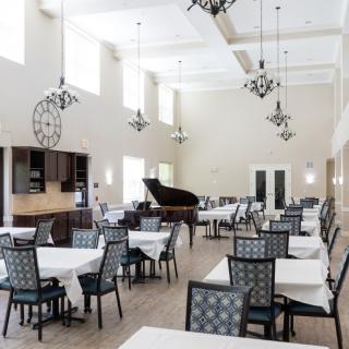 A modern dining room with elegantly set tables and a grand piano.