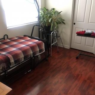 A cozy bedroom with a single bed, wooden flooring, and a potted plant by the window.