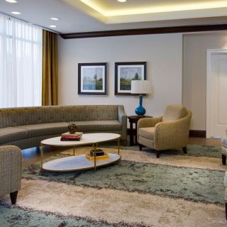 A modern living room featuring a curved sofa, armchairs, and a round coffee table on a plush carpet.