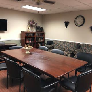 A well-furnished meeting room equipped with a large conference table, chairs, and multimedia facilities.