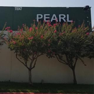 A view of the building with the sign 'PEARL', framed by flowering trees.