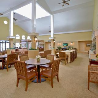 A spacious dining area with several tables and chairs, featuring yellow walls and ceiling fans.
