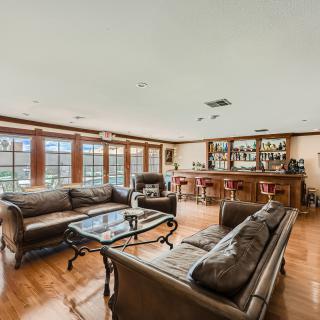 A spacious living room with elegant sofas, a central coffee table, and a bar area near large windows.