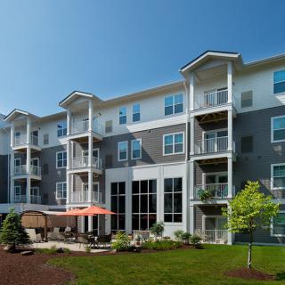 Modern apartment building with balconies and outdoor seating area.