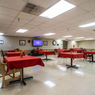 A dining room with red tablecloth-covered tables and a television on the wall.