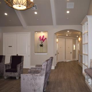 A modern waiting room with comfortable seating, tasteful lighting, and a hallway leading to another area.