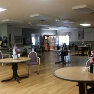 An empty dining area with tables and chairs arranged on a wooden floor.