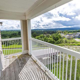 A spacious balcony offering a scenic view of lush green landscapes under a cloudy sky.