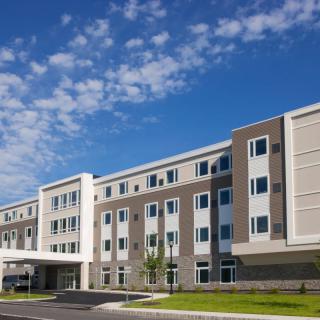 A modern hotel building with a clear blue sky and scattered clouds.