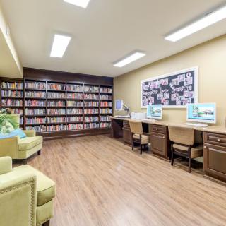 A modern library interior with bookshelves, computers, and a seating area.