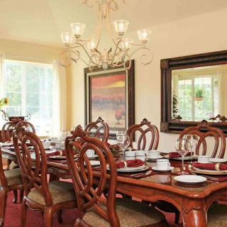 An elegant dining room with a beautifully set table, ornate chairs, and a chandelier.