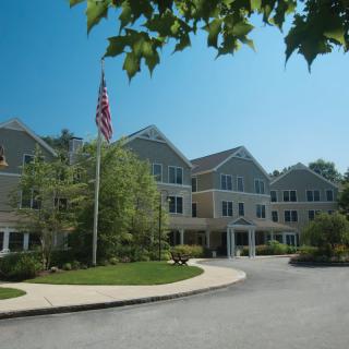 A residential building with an American flag and surrounding greenery on a sunny day.