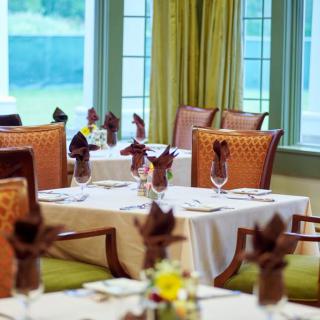 An elegant restaurant dining room with tables set and napkins folded.