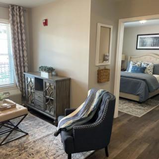 A stylishly designed living area with a view into the bedroom, featuring modern decor and comfortable furnishings.
