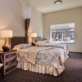 A cozy bedroom with two neatly made beds and elegant lamps on the bedside tables.