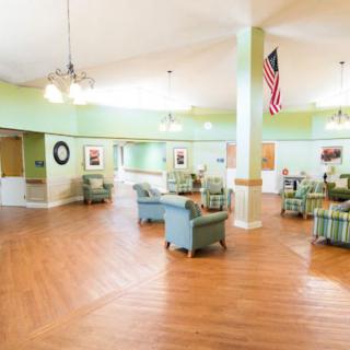 A spacious and well-lit lounge area with comfortable seating and a large United States flag displayed.