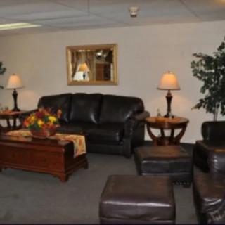 A cozy living room featuring a black leather sofa, a wooden coffee table with floral decorations, and warm lighting from table lamps.