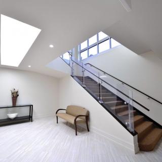 A modern interior featuring a sleek staircase, skylight, and minimalist furniture.
