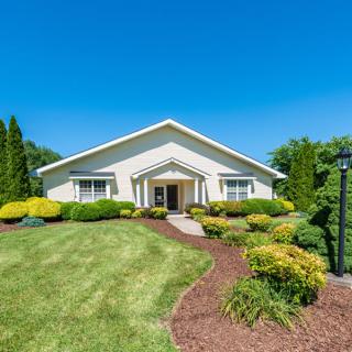 A well-maintained residential property with a lush green lawn and landscaped garden under a clear blue sky.
