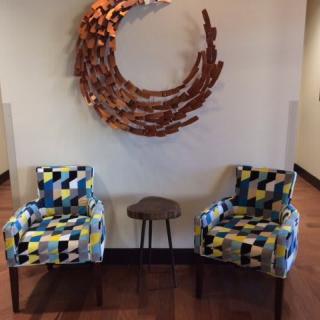 A modern interior setup featuring two colorful chairs and a small table, complemented by a circular wall artwork.