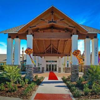 A grand entrance with a red carpet leading to a tropical-themed building under a clear blue sky.