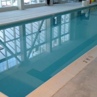 An indoor swimming pool with clear water and reflections from the windows.