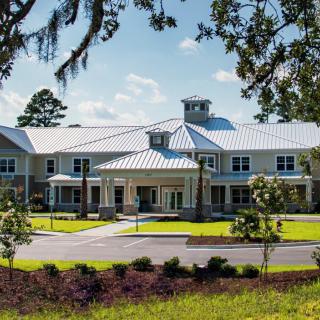 A large, elegant building surrounded by greenery under a clear blue sky.