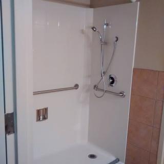 An accessible shower stall with a grab bar and adjustable showerhead.