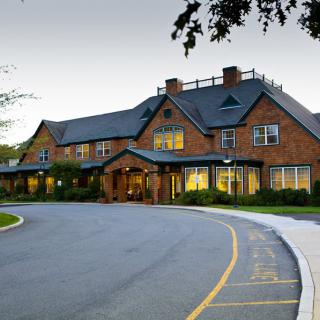 A charming brick hotel with a circular driveway, set against an evening sky.