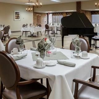 An elegant dining area with table settings and a grand piano.
