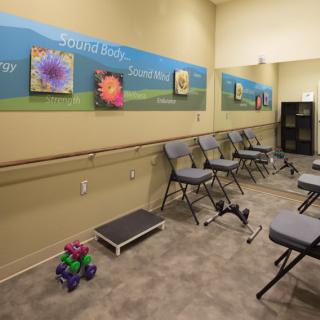 A small exercise room with chairs, a mirror, and various exercise equipment.