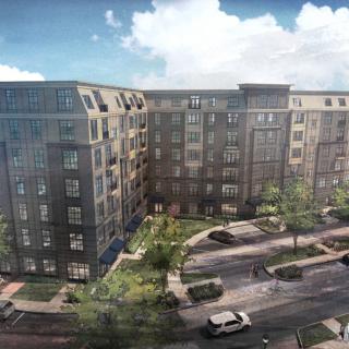 A modern residential apartment complex with landscaped surroundings and parked cars.