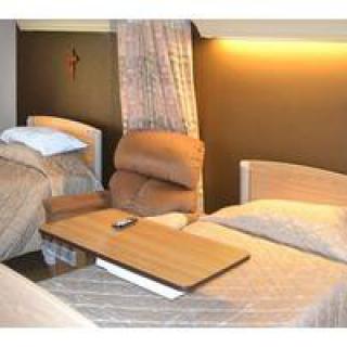 A hospital room with two beds and a reclining chair.