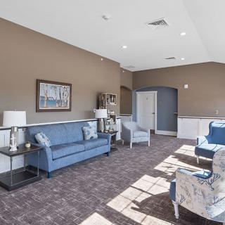 A cozy living room with blue sofas, chairs, and natural lighting.