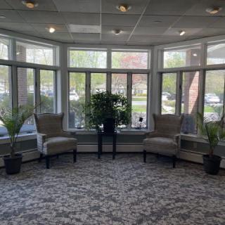 A cozy lobby area with large windows, comfortable chairs, and potted plants.