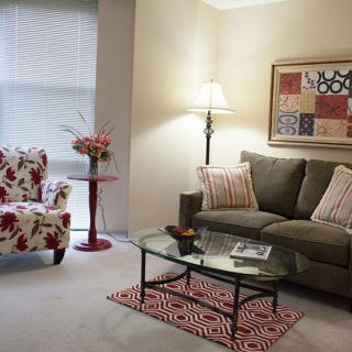 A cozy living room featuring a sofa, floral armchair, and glass coffee table.