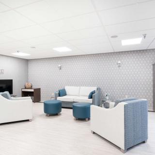 A modern living room with minimalist decor, featuring a sofa, chairs, and coffee tables.