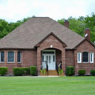 A brick suburban house with a well-maintained lawn.