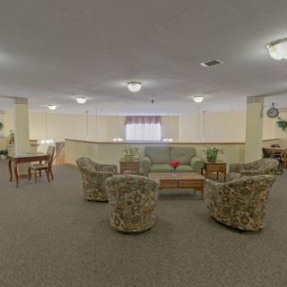 A spacious living room with a seating area and carpeted floor.