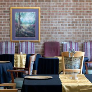 A beautifully arranged restaurant interior featuring tables draped in elegant fabrics and an artistic painting on the wall.