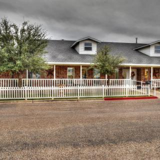 A suburban house with a white picket fence under a cloudy sky.
