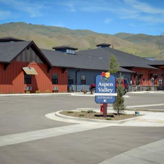 A red and black building complex with a sign in the foreground, set against a backdrop of mountains.
