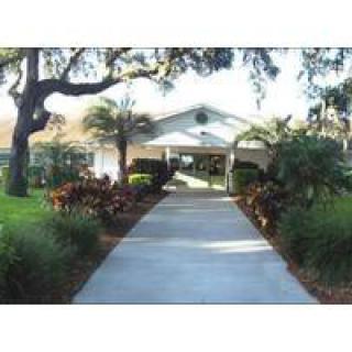 A beautifully landscaped entrance pathway leading to a building, surrounded by lush greenery and palm trees.