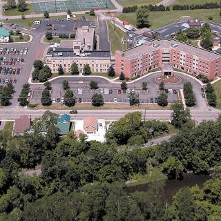 Aerial view of a large building complex with parking lots and surrounding greenery.