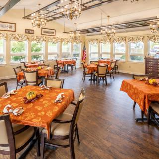 A spacious dining area with beautifully set tables and elegant chandeliers.