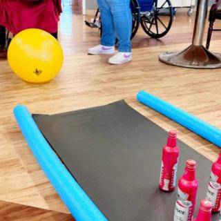 A setup for an indoor exercise session with a yoga mat, foam rollers, and a yellow ball.