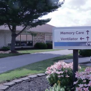 A sign outside a healthcare facility directing to memory care and ventilator units.